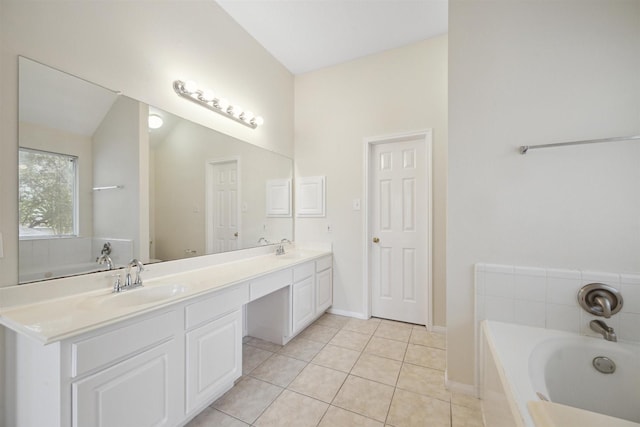 bathroom featuring tile patterned flooring, vanity, and tiled bath