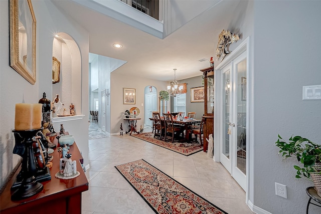 hall featuring light tile patterned floors, french doors, and a notable chandelier