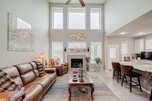 living room featuring light tile patterned floors, a wealth of natural light, a fireplace, and a towering ceiling