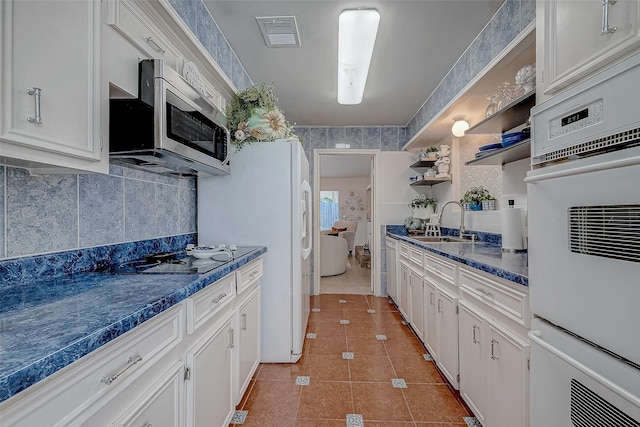 kitchen with black electric cooktop, white cabinetry, sink, and light tile patterned floors