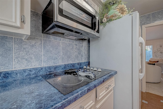 kitchen with decorative backsplash, black electric cooktop, white refrigerator, tile walls, and tile patterned flooring