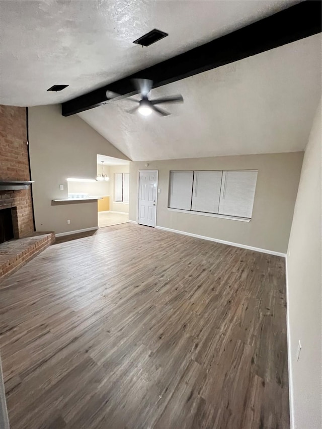 unfurnished living room with a textured ceiling, lofted ceiling with beams, wood-type flooring, and a fireplace