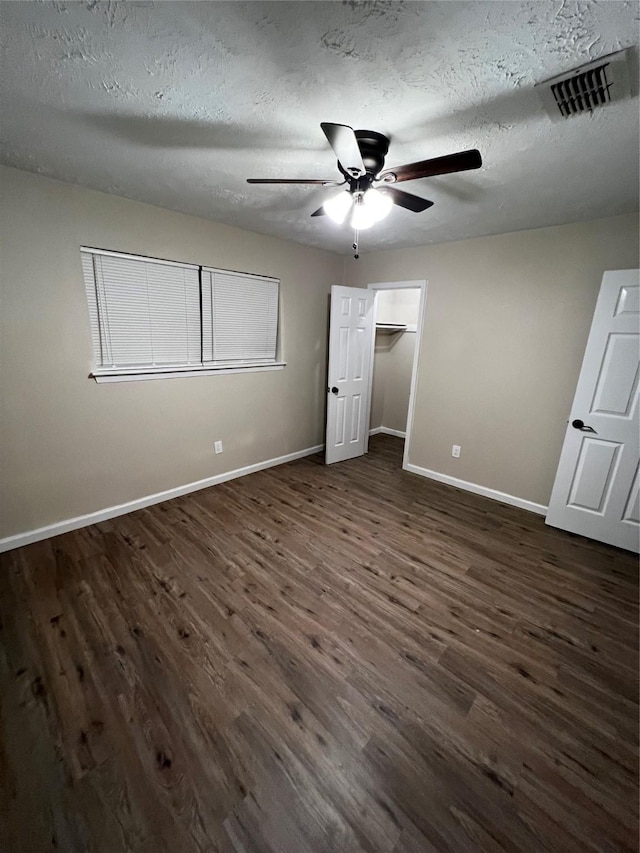 unfurnished bedroom featuring a textured ceiling, ceiling fan, and dark wood-type flooring