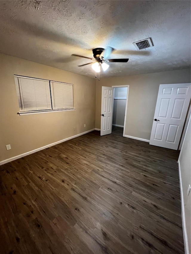 unfurnished bedroom with a textured ceiling, ceiling fan, and dark hardwood / wood-style floors