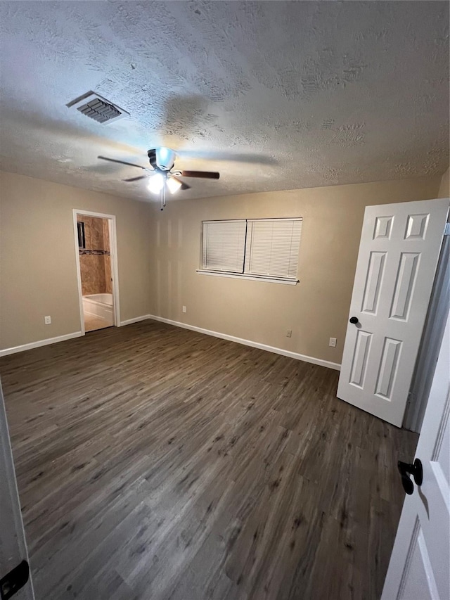 unfurnished bedroom featuring ceiling fan, dark hardwood / wood-style flooring, a textured ceiling, and connected bathroom