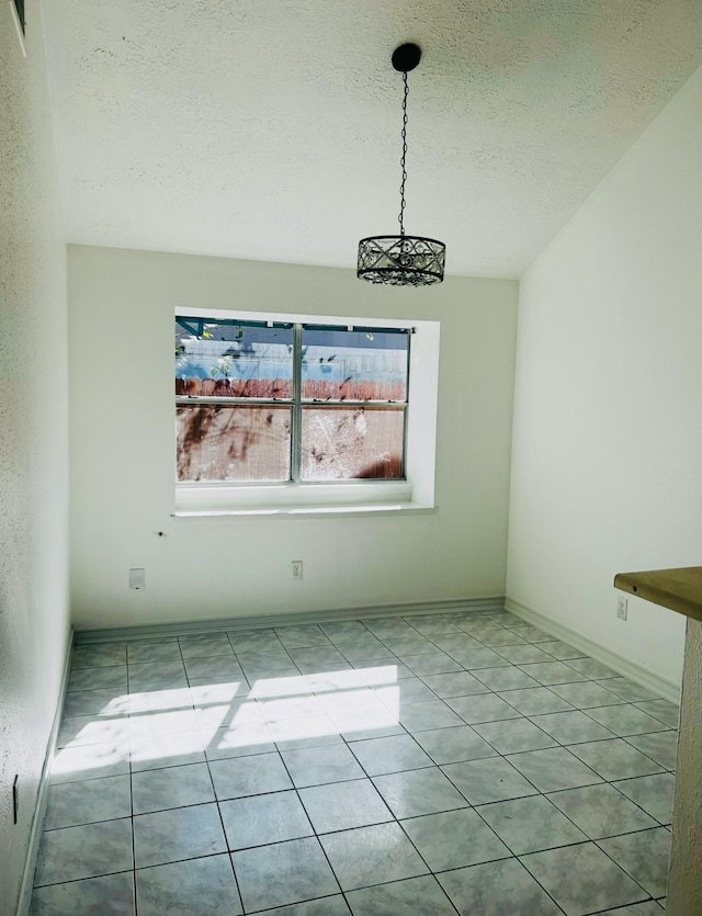 unfurnished dining area with a notable chandelier, light tile patterned flooring, and a textured ceiling