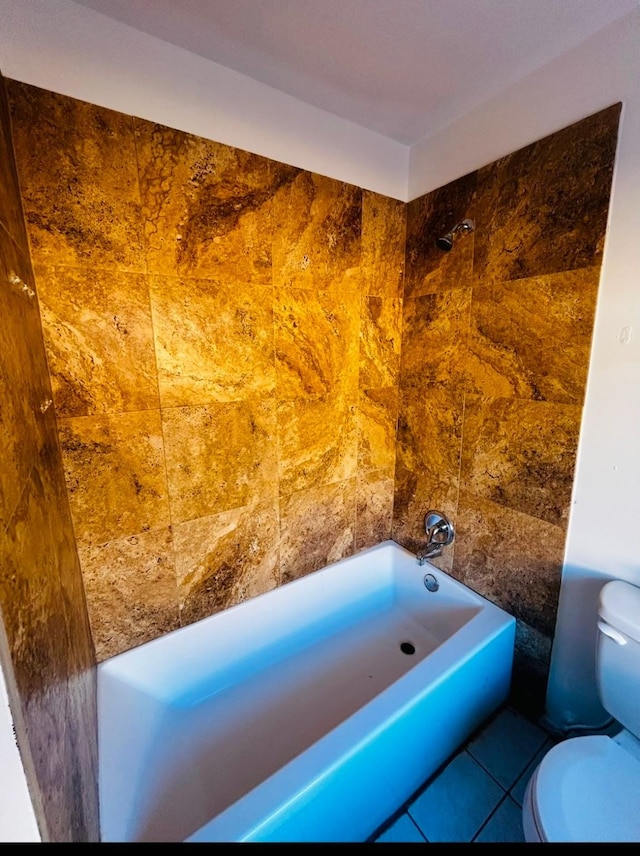 bathroom with tile patterned floors, a washtub, and toilet