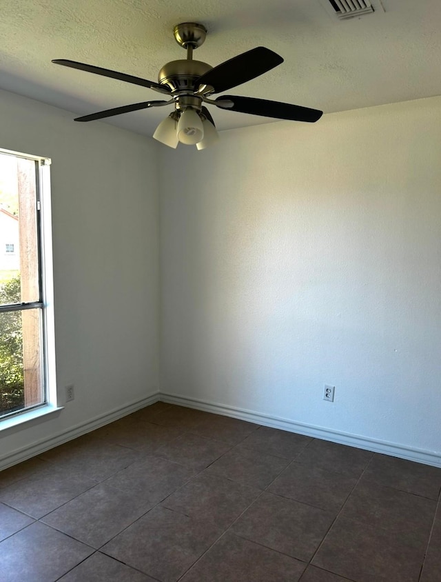 spare room with ceiling fan and dark tile patterned floors