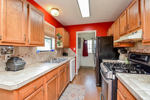 kitchen with white dishwasher, stainless steel range with gas cooktop, sink, and tile countertops