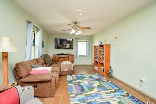 living room featuring ceiling fan, wood-type flooring, and a textured ceiling