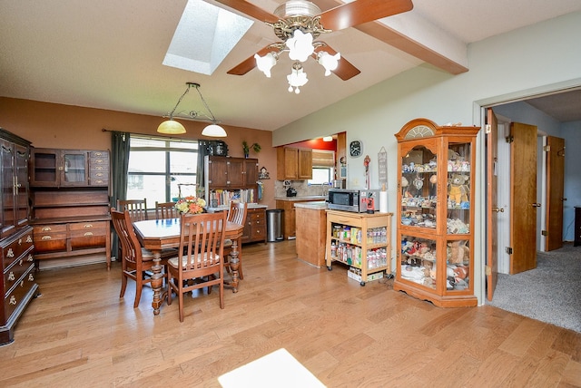 dining space featuring ceiling fan, light hardwood / wood-style floors, and lofted ceiling with skylight