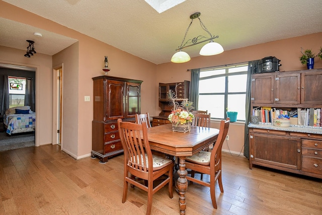 dining space with a textured ceiling and light hardwood / wood-style flooring