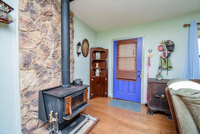 entryway featuring a textured ceiling, light wood-type flooring, and a wood stove