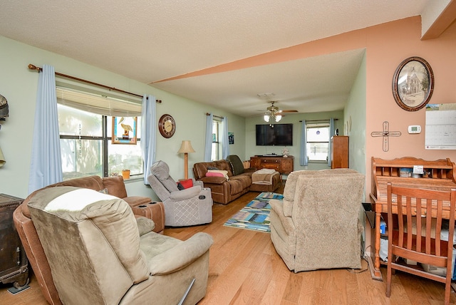 living room featuring a textured ceiling, light hardwood / wood-style flooring, and ceiling fan