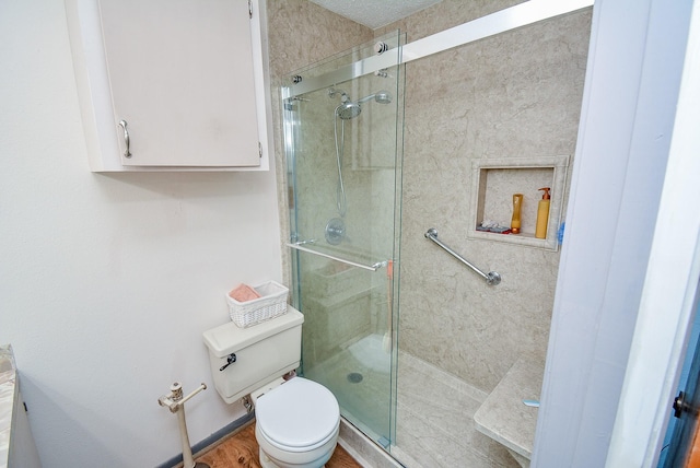 bathroom featuring toilet, an enclosed shower, and wood-type flooring