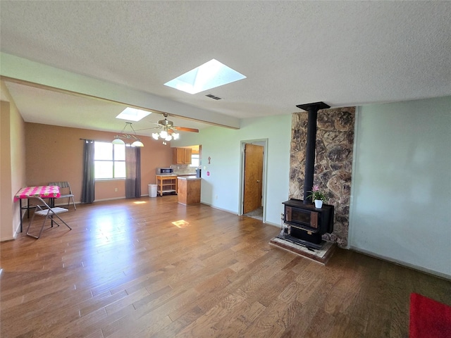 1495 W Bayshore Dr, Palacios, TX 77465 - living room featuring a wood stove, light wood-style floors, a skylight, a textured ceiling, and baseboards
