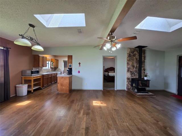 1495 W Bayshore Dr, Palacios, TX 77465 - kitchen with a skylight, stainless steel microwave, brown cabinets, a textured ceiling, and a wood stove