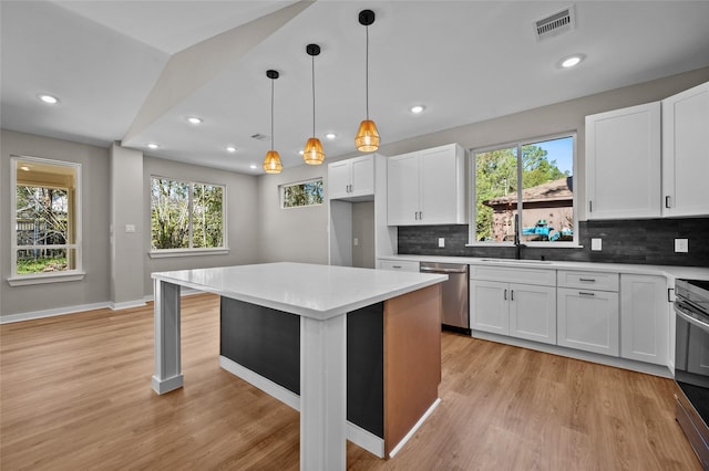 kitchen with stainless steel appliances, white cabinetry, and a healthy amount of sunlight