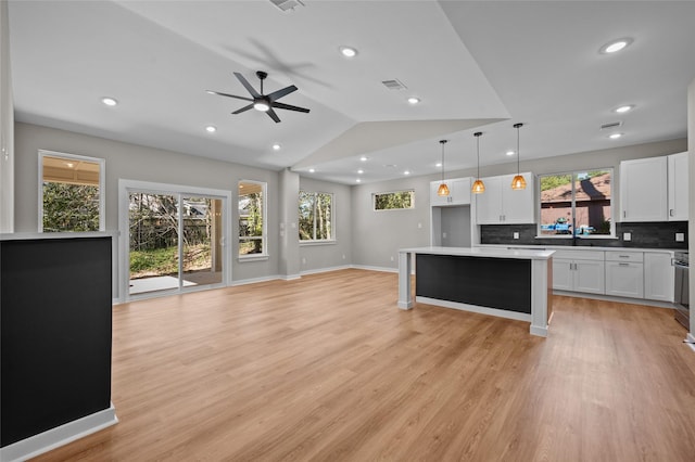 kitchen with light wood-type flooring, decorative light fixtures, white cabinetry, and lofted ceiling