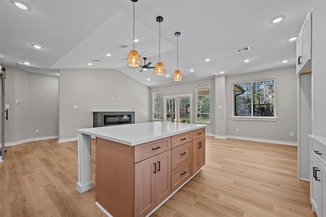 kitchen with white cabinetry, light hardwood / wood-style flooring, a center island, and hanging light fixtures