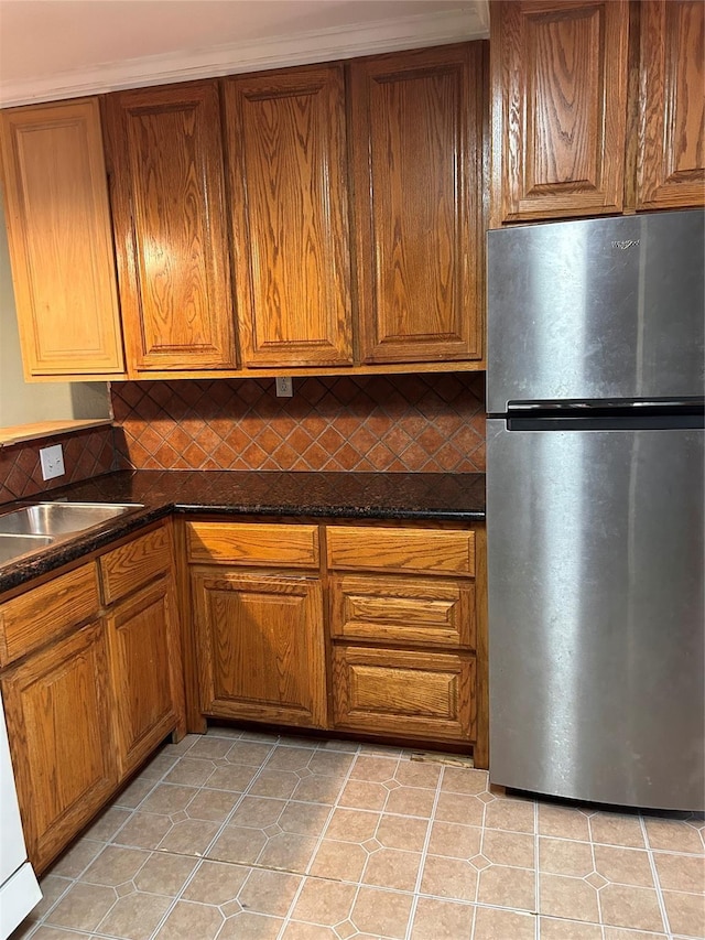 kitchen featuring stainless steel refrigerator, decorative backsplash, sink, and light tile patterned floors