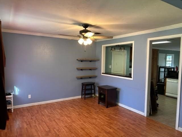 empty room featuring hardwood / wood-style flooring, ceiling fan, and ornamental molding