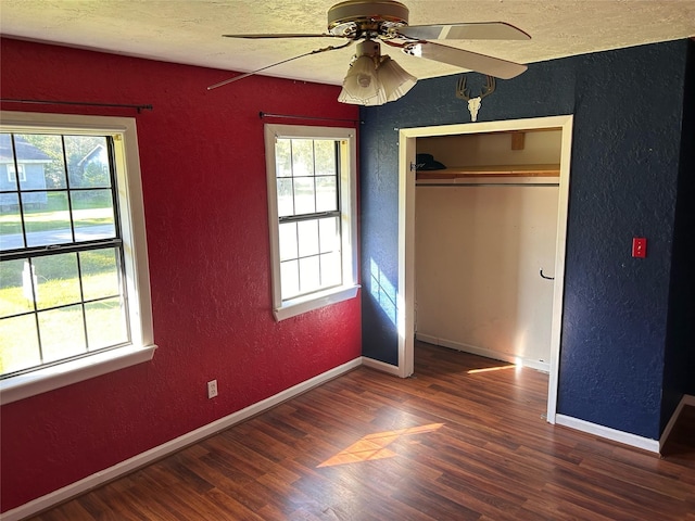 unfurnished bedroom with a textured ceiling, ceiling fan, a closet, and dark hardwood / wood-style floors