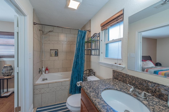 full bathroom with shower / bath combo, a textured ceiling, toilet, vanity, and hardwood / wood-style flooring