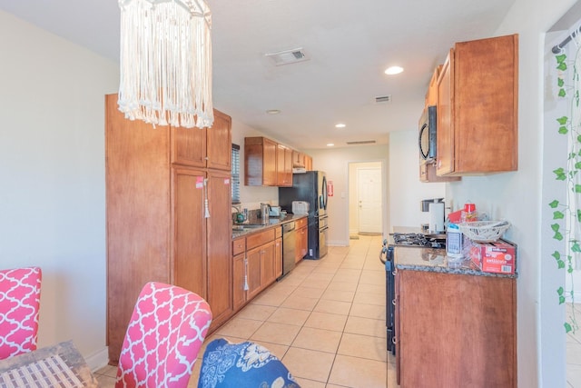 kitchen with dark stone counters, sink, stainless steel dishwasher, light tile patterned flooring, and range with gas cooktop