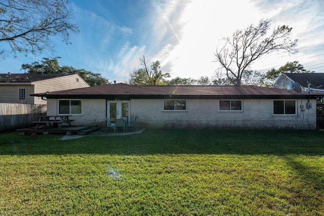 rear view of property with a lawn, a patio area, and french doors