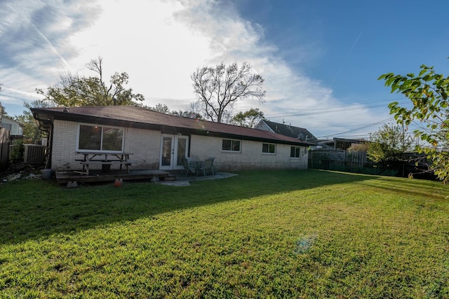 rear view of property with french doors, central air condition unit, and a lawn