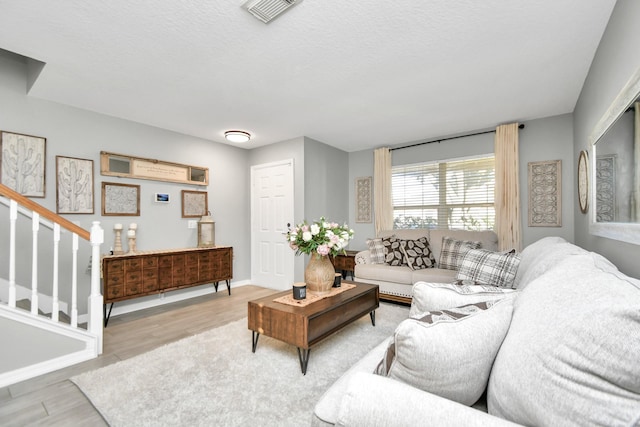 living room featuring light wood-type flooring and a textured ceiling