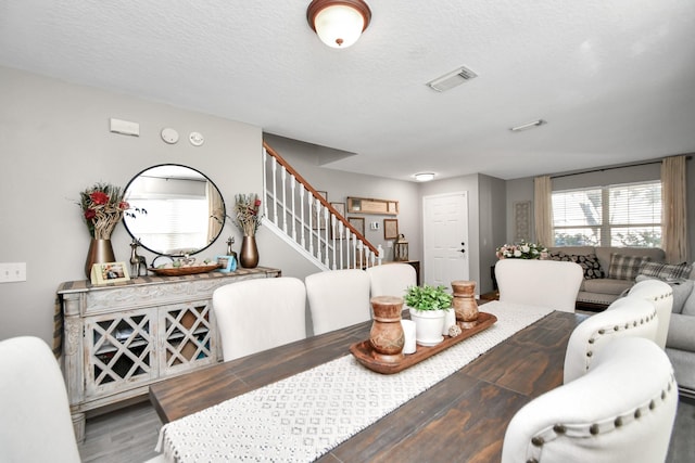 dining space with hardwood / wood-style floors and a textured ceiling