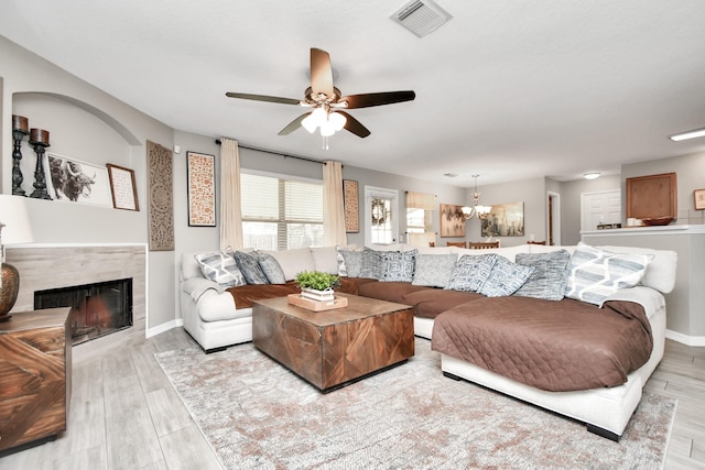 living room featuring ceiling fan with notable chandelier and light wood-type flooring