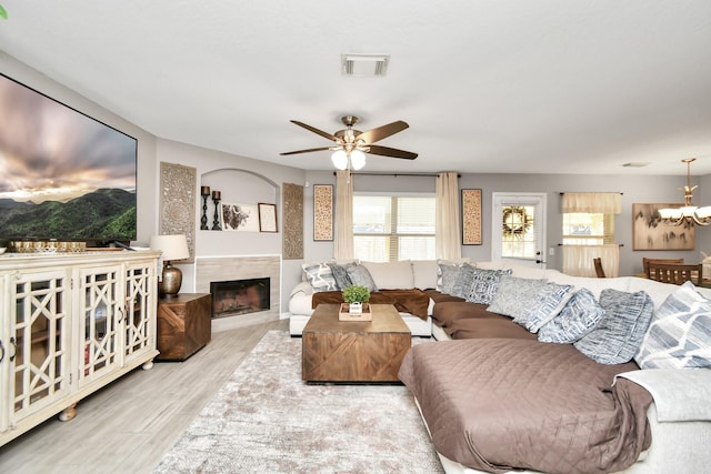 living room with ceiling fan with notable chandelier and light wood-type flooring