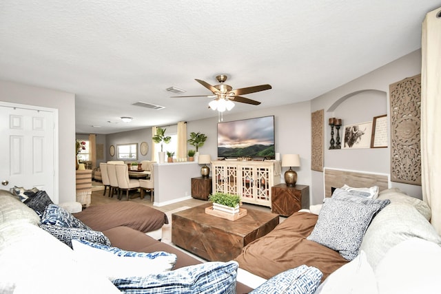 living room featuring ceiling fan and a textured ceiling