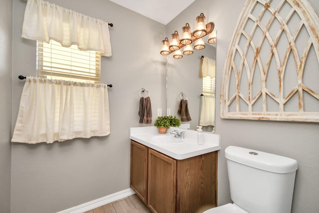 bathroom with wood-type flooring, vanity, a healthy amount of sunlight, and toilet