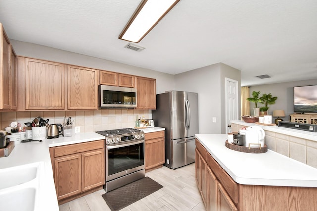 kitchen with light hardwood / wood-style flooring, sink, appliances with stainless steel finishes, and tasteful backsplash