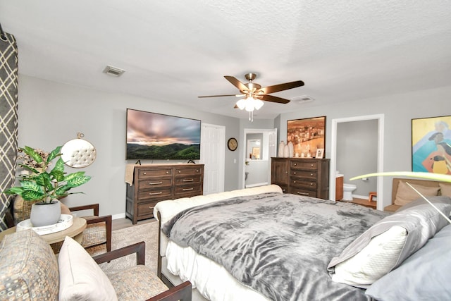 bedroom featuring a textured ceiling, ensuite bath, and ceiling fan