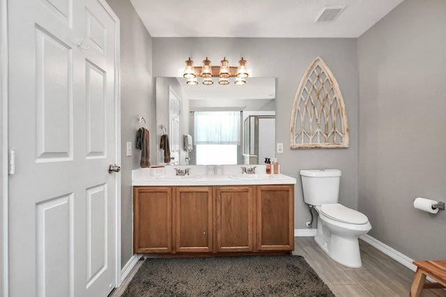 bathroom featuring hardwood / wood-style floors, vanity, a shower with door, and toilet