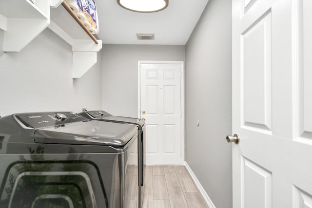 washroom with light hardwood / wood-style flooring and washer and clothes dryer