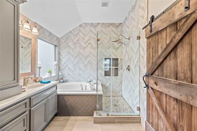 bathroom featuring vanity, tile patterned floors, vaulted ceiling, tile walls, and independent shower and bath