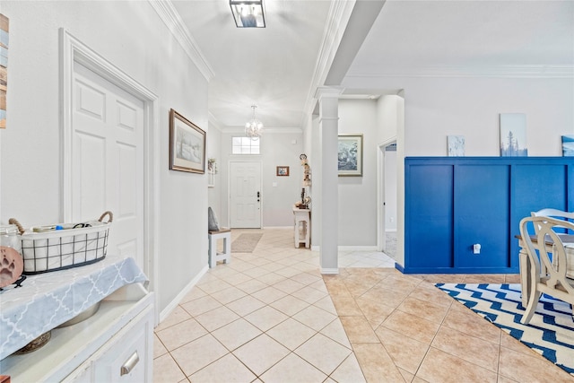 entryway with ornate columns, crown molding, light tile patterned floors, and a notable chandelier