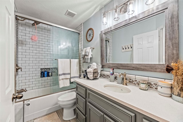 full bathroom with tasteful backsplash, vanity, a textured ceiling, shower / bath combination with glass door, and toilet