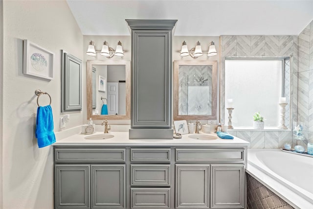 bathroom featuring tiled bath, a wealth of natural light, and vanity