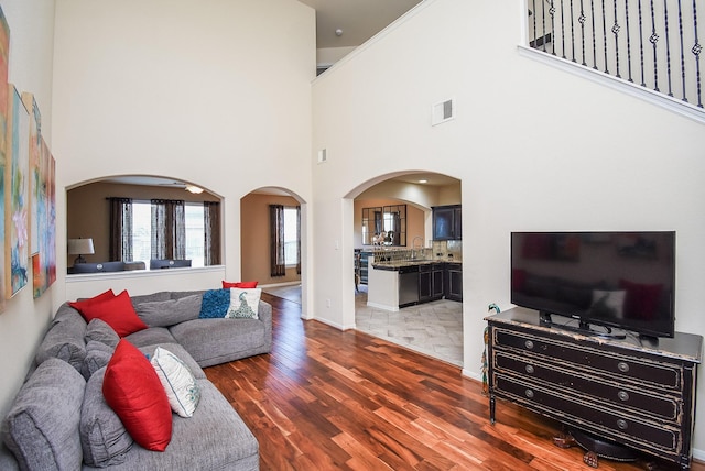 living room with sink, a towering ceiling, and dark hardwood / wood-style floors