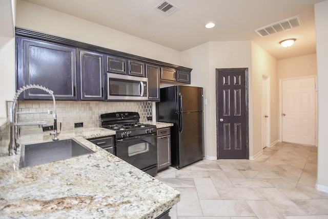 kitchen featuring tasteful backsplash, light stone counters, sink, and black appliances