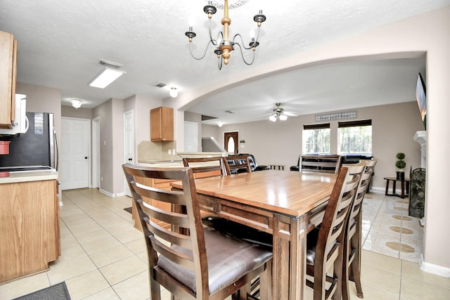 tiled dining space featuring a textured ceiling and ceiling fan with notable chandelier