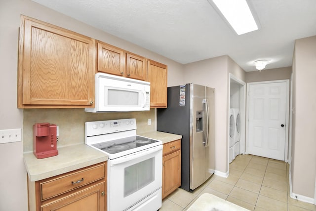 kitchen with washer and clothes dryer, white appliances, and light tile patterned floors