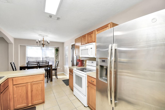 kitchen featuring white appliances, hanging light fixtures, light tile patterned floors, and an inviting chandelier